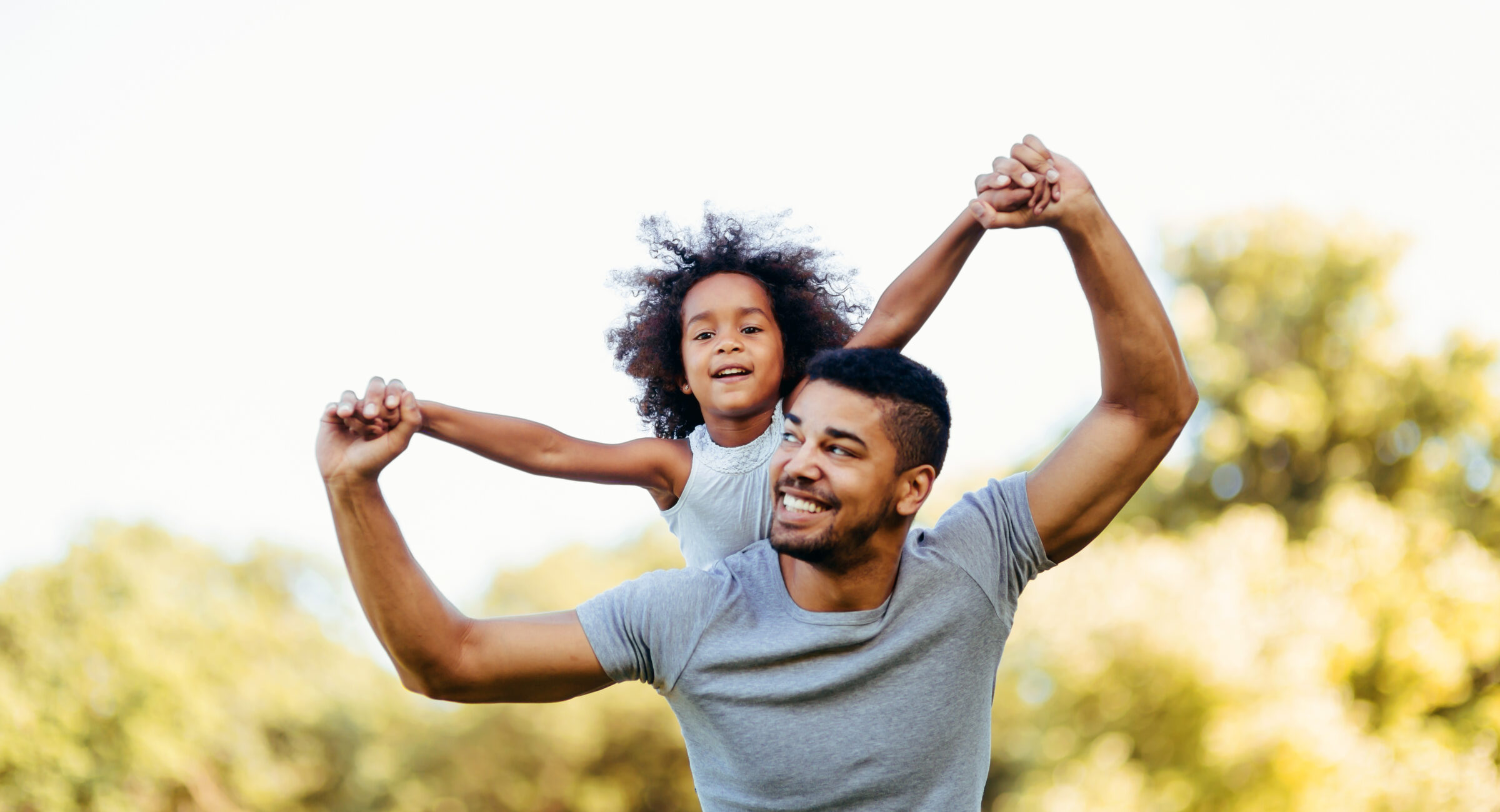 Portrait of young father carrying his daughter on his back in nature